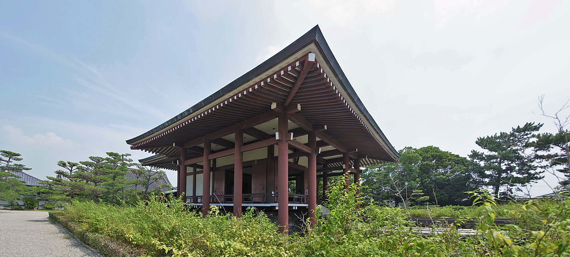 青空の下に立つ中宮寺の本堂と境内の緑