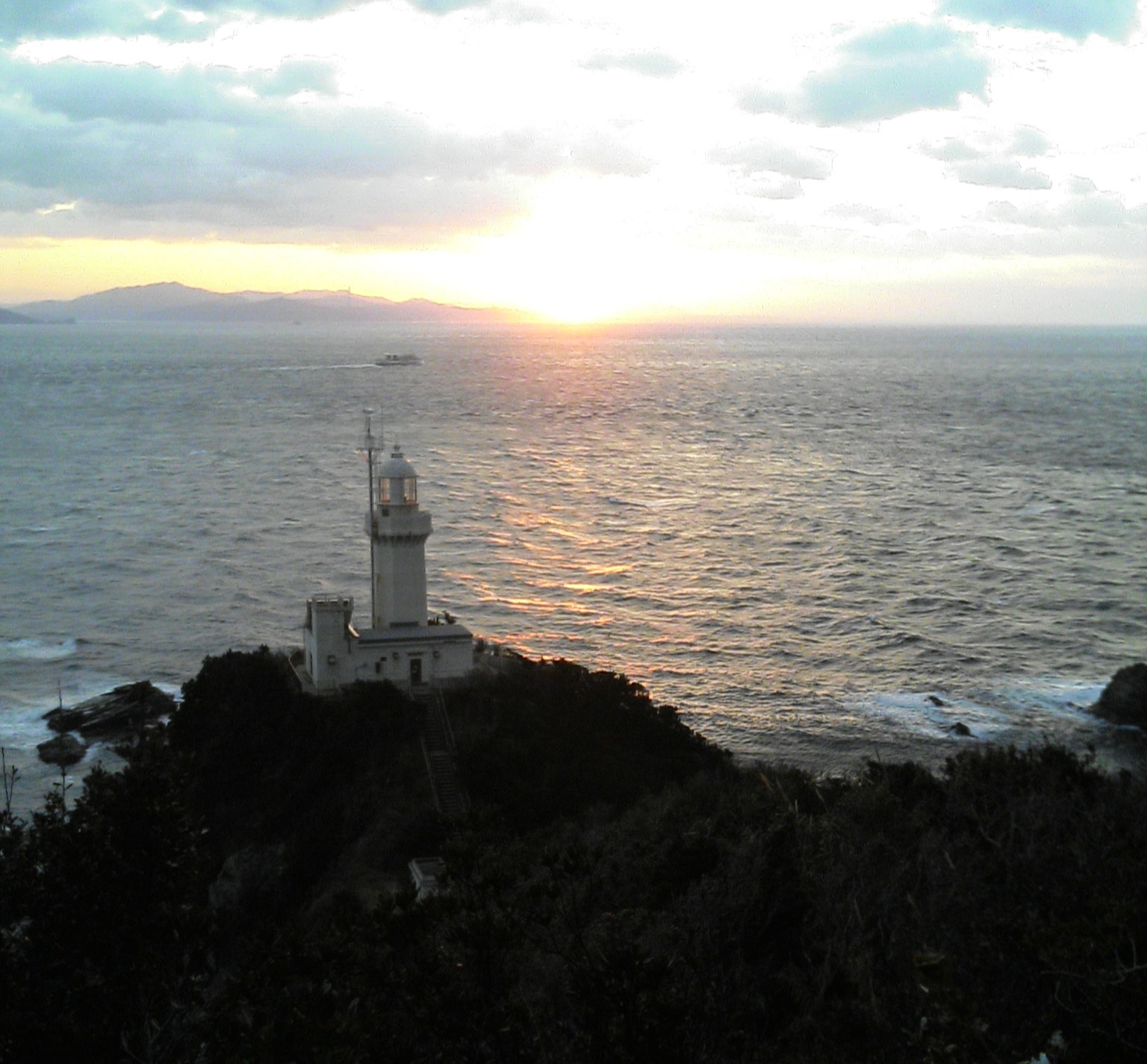 夕日に照らされる佐田岬灯台と佐田岬半島の海