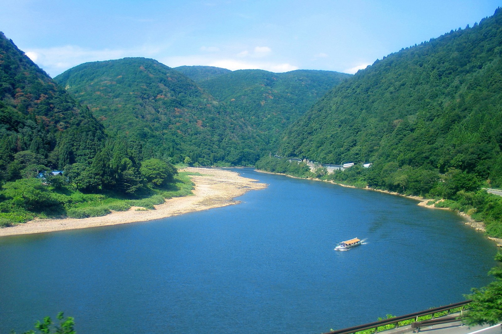緑深い山並みに挟まれた最上峡と最上川舟下りの遊覧船